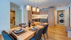 Eine moderne Küche mit Holzausbau, einer integrierten Waschmaschine und einem Essbereich mit Holztisch, gedeckt für zwei Personen.