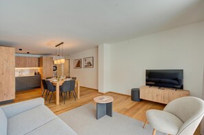 Una sala de estar moderna con un sofá, una televisión y un comedor con sillas y una mesa.