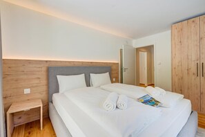 A hotel room with a large bed, a wooden headboard, a bedside table, and a wardrobe. - Residenza Castanea 109 San Bernardino Alpine Apartments, San Bernardino, Switzerland (San Bernardino)