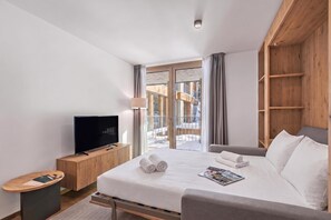 Habitació d'hotel amb un llit, una televisió, un armari de fusta i vista a l'exterior.