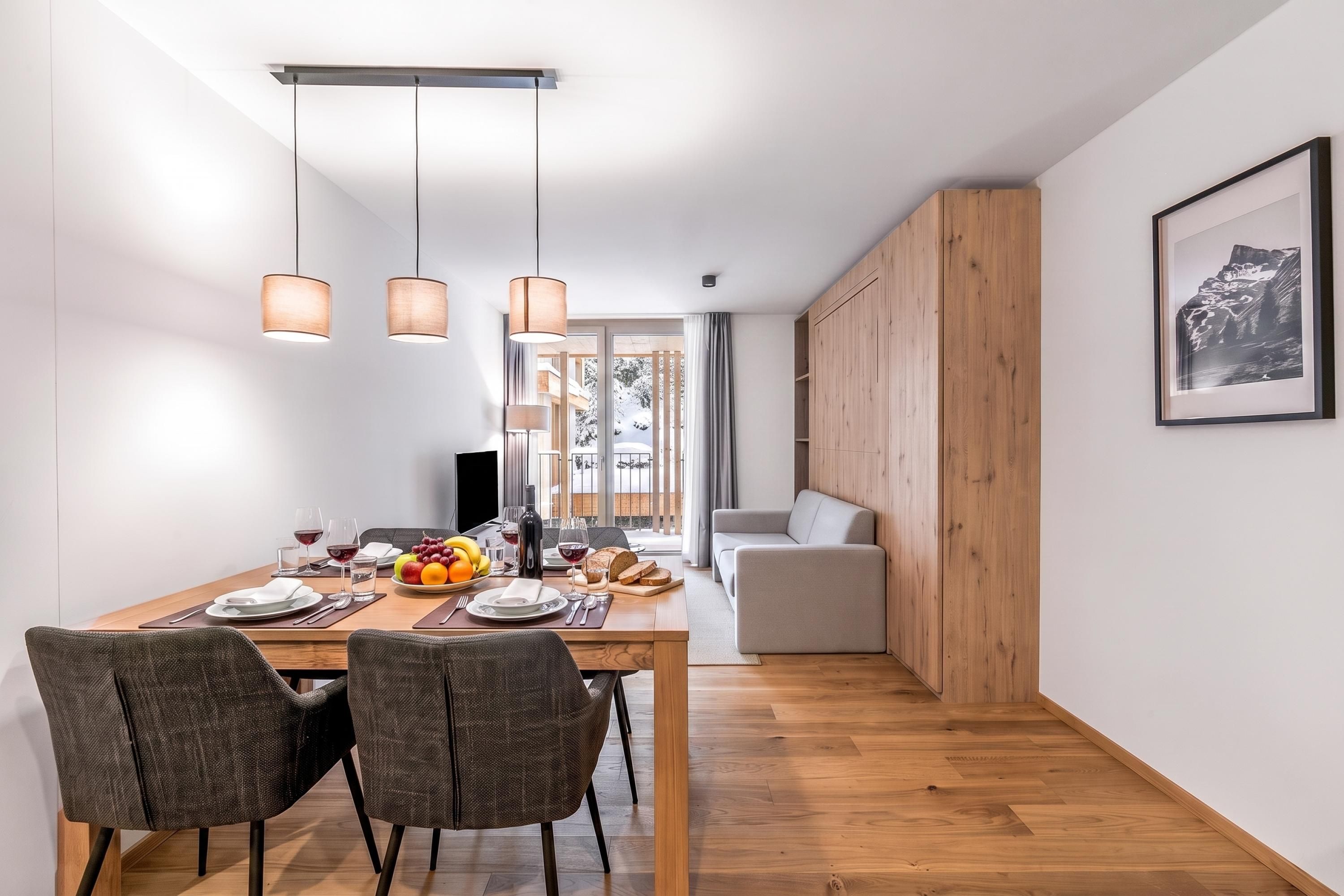 Ein moderner Essbereich mit Holztisch, Stühlen und Pendelleuchten.