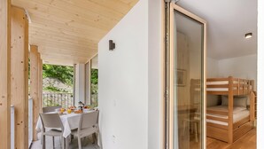 Ein modernes Interieur mit Essbereich, einem Bett mit Holz Kopfteil und einer Glastür, die zu einem Außenbereich führt.