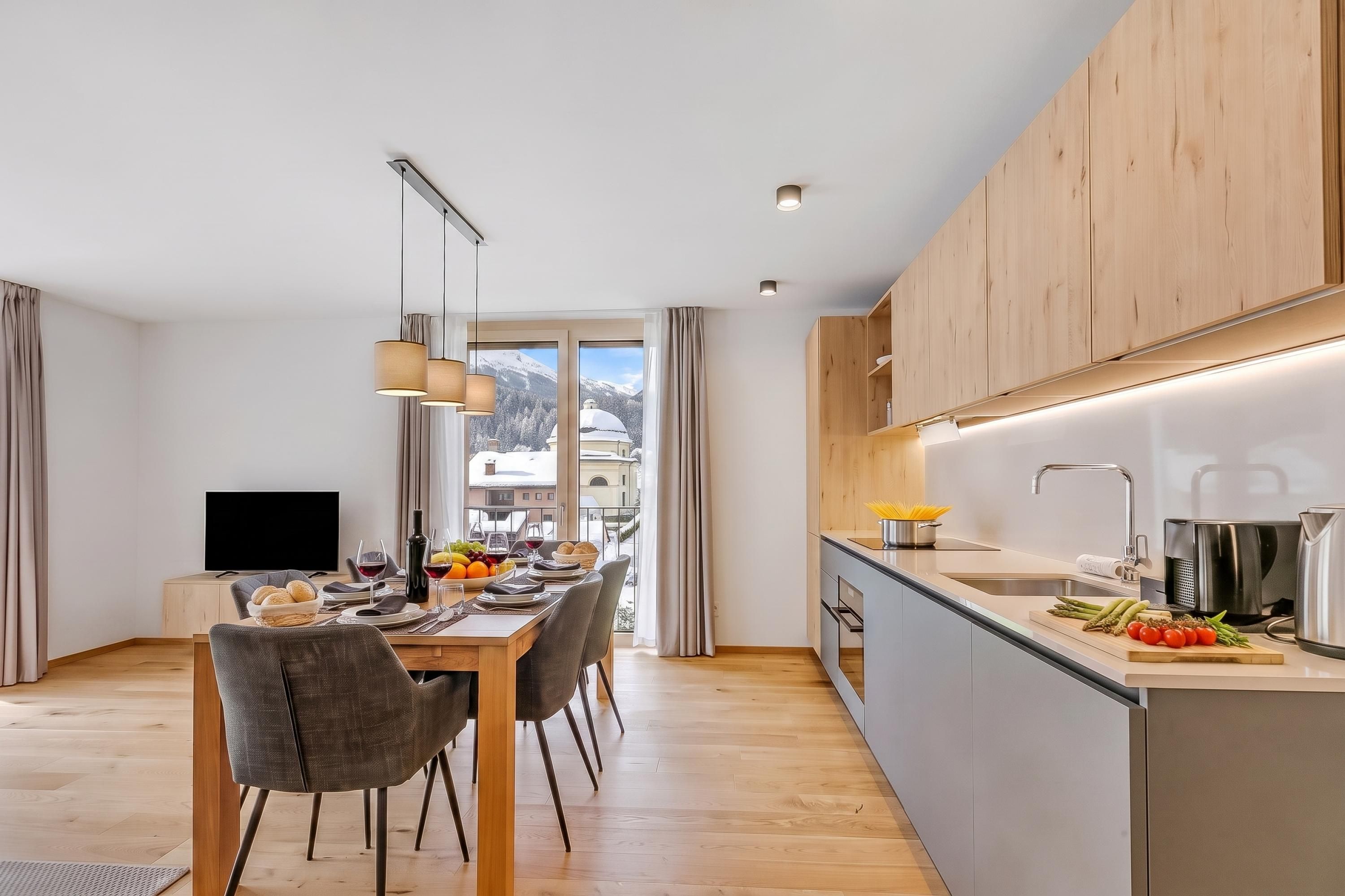 Eine moderne Küche mit Essbereich, Holzschränken und Blick auf eine verschneite Landschaft.