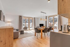 Eine moderne Küche mit Essbereich, Holzboden und großen Fenstern, die einen Blick auf eine verschneite Landschaft bieten.