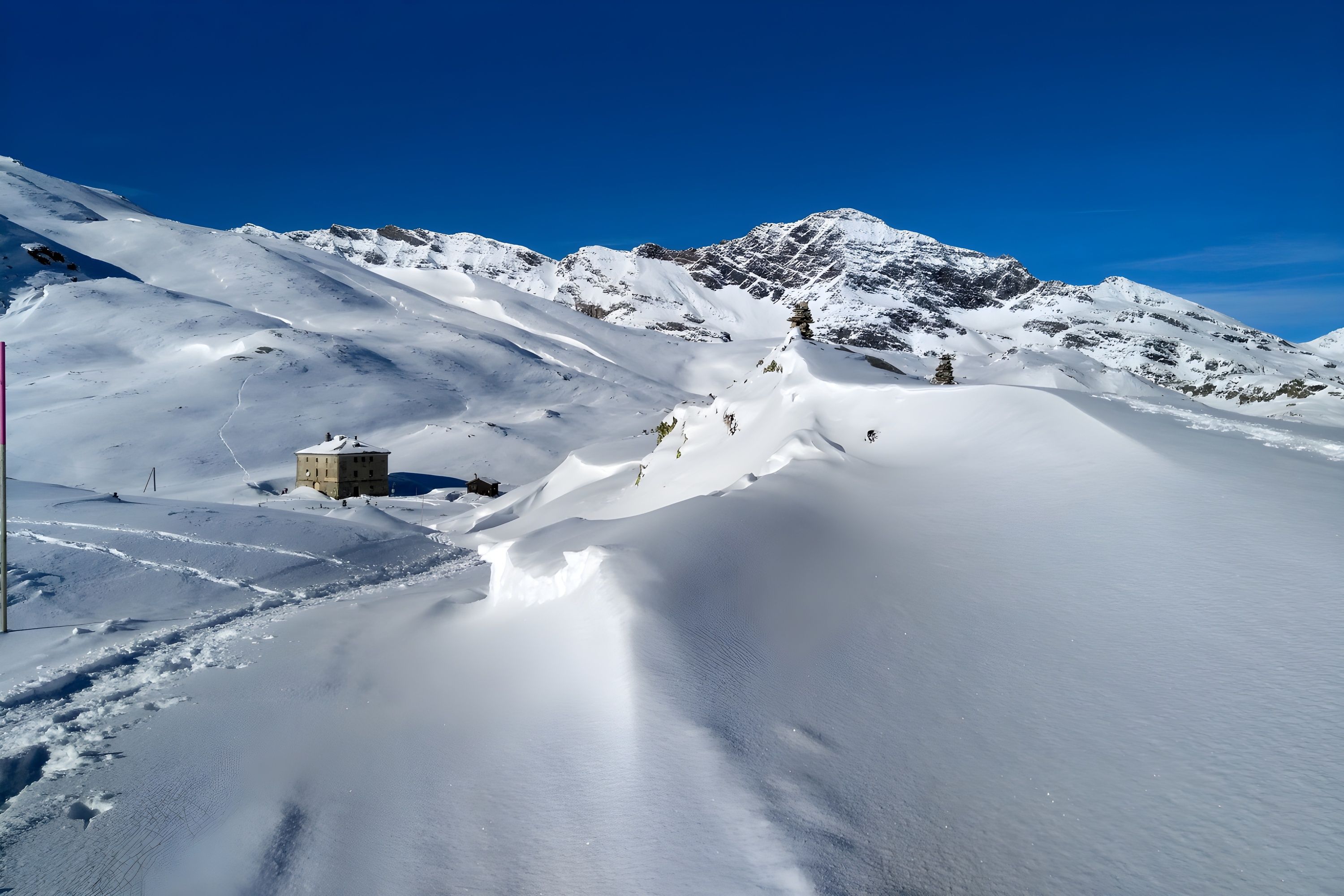 Eine verschneite Berglandschaft bei klarblauem Himmel.