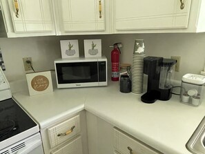 A kitchen with white cabinets, a microwave, a blender, and a coffee maker.