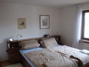 A bedroom with a bed, two bedside tables, a nightstand, a lamp, and two framed pictures on the wall. - Oberlech in Lech by Interhome (Lech)