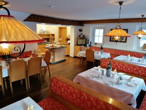 A restaurant with multiple dining areas, including booths and tables, with overhead lamps and a kitchen in the background. - nahe den Skigebieten und Ausgangspunkt zu Sehenswürdigkeiten by Interhome (Mittersill)