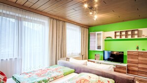 A hotel room with a bed, a sofa, a TV, and a green wall. - nahe den Skigebieten und Ausgangspunkt zu Sehenswürdigkeiten by Interhome (Mittersill)