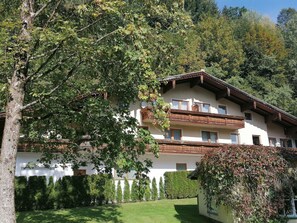 Ein traditionelles Chalet mit weißer Fassade, hölzernen Balkonen und einem gepflegten Garten.