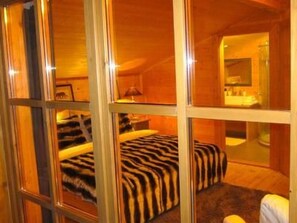 Ein Zimmer mit einem Bett, einem Sessel und einem Spiegel.