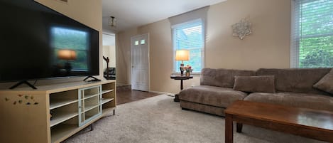 Un salon avec un téléviseur, un canapé, une table basse et une lampe.