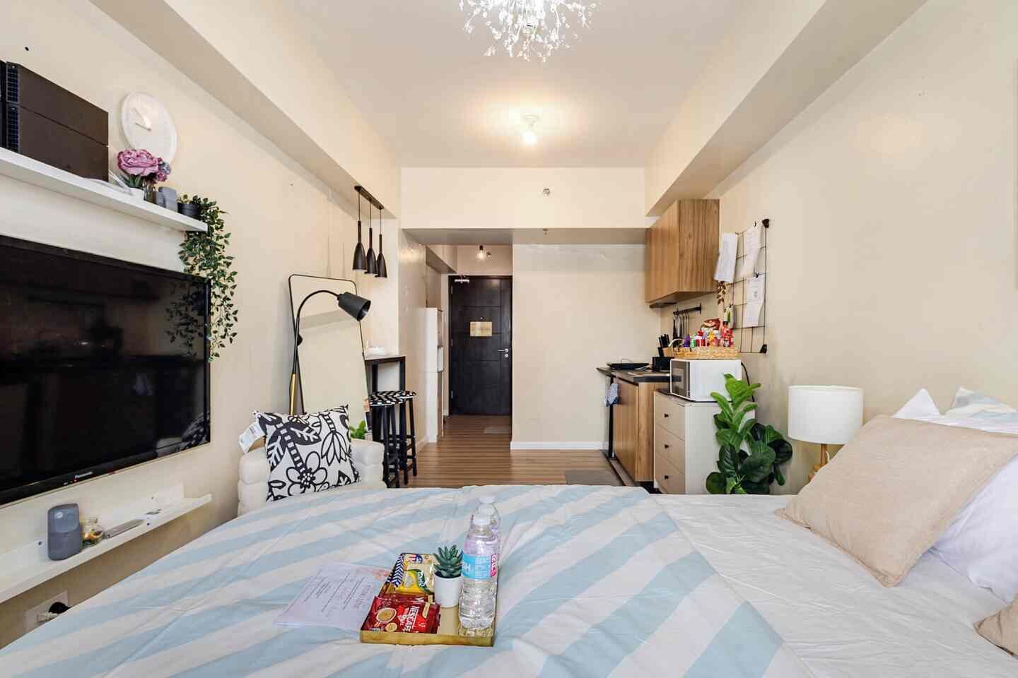 Ein Hotelzimmer mit Bett, Fernseher, Schreibtisch, Küchenzeile und Bad.