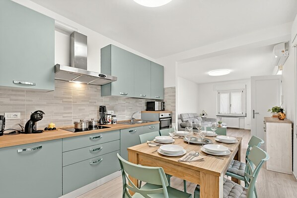 Een moderne keuken met een centraal eiland, inbouwapparatuur en een eethoek met een tafel gedekt voor vier personen.