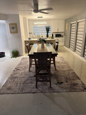 A dining area with a table, chairs, a ceiling fan, and a kitchen in the background. - Charming 3-bedroom house with pool in beautiful Palm Bay (Palm Bay)