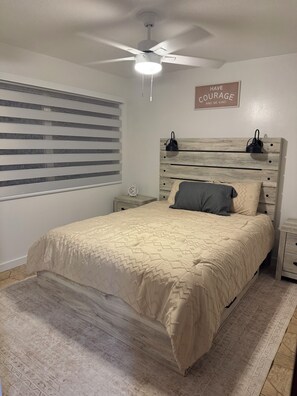 A bedroom with a bed, a ceiling fan, a bedside table with a clock, and a motivational quote on the wall. - Charming 3-bedroom house with pool in beautiful Palm Bay (Palm Bay)