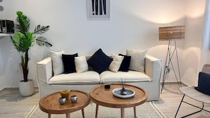 A living room with a sofa, two small tables, a floor lamp, and a potted plant. - F11 Appartement Douillet à La Marsa (La Marsa)