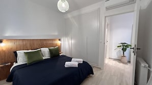 A bedroom with a bed, bedside tables, a wooden headboard, a hanging light fixture, a closet, and a potted plant. - F11 Appartement Douillet à La Marsa (La Marsa)
