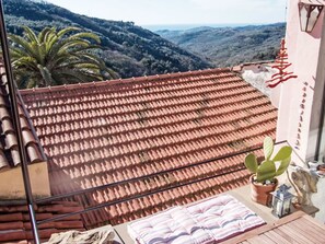 A balcony with a tiled roof, a potted plant, and a cushion. - Due Anime Felice by Interhome (Vasia)