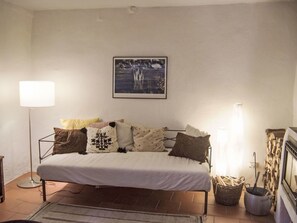 Une chambre à coucher avec un lit, des oreillers, une lampe sur pied, un tableau encadré au mur et une cheminée avec des bûches.