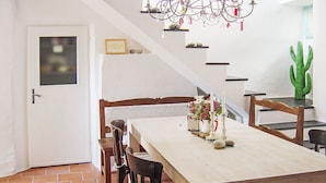 A dining area with a wooden table and chairs, a chandelier, and a cactus decoration. - Due Anime Felice by Interhome (Vasia)