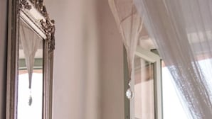 A room with a large mirror, a window with a curtain, and a red bench. - Due Anime Felice by Interhome (Vasia)