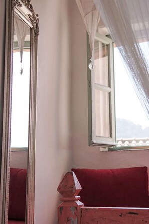 A room with a large mirror, a window with a curtain, and a red bench. - Due Anime Felice by Interhome (Vasia)