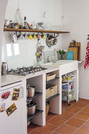 A compact kitchen with a gas stove, shelves, and hanging utensils. - Due Anime Felice by Interhome (Vasia)