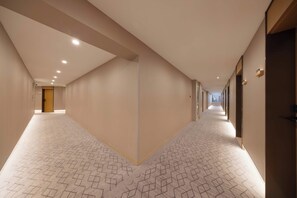 A hotel corridor with patterned carpet, recessed lighting, and doors on both sides. - Baman Hotel  (Beijing)