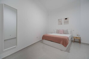 Ein schlicht eingerichtetes Schlafzimmer mit Bett, Nachttischen und einem Kleiderschrank.
