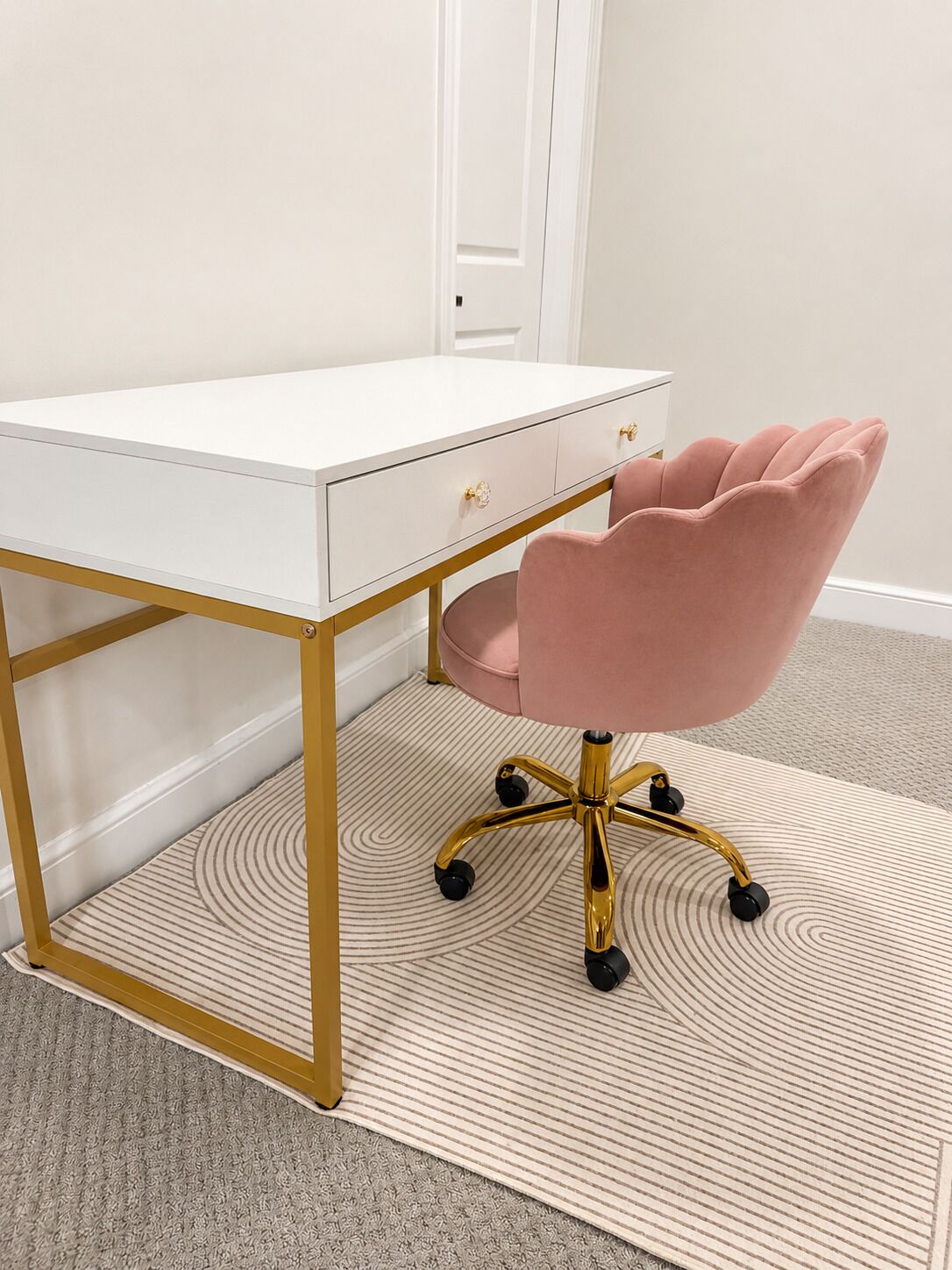 A white desk with gold legs and a pink chair with a five-star base.