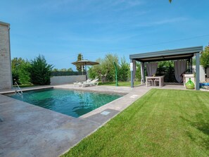A swimming pool with a covered patio area, lounge chairs, and a small table with a green bottle. - Villa Maslina by Interhome (Dracevac)