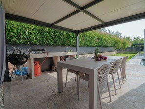 An outdoor patio with a grill, table, chairs, and a wall of greenery. - Villa Maslina by Interhome (Dracevac)