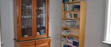 A room with a wooden cabinet and a tall bookshelf filled with books and binders.