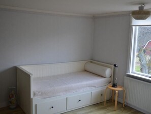 A small, white, single-bed room with a window, a radiator, and a lamp on a small table. - Schönes Ferienhaus in Småland mit Sauna, Bootssteg zum Schwimmen mit Ruderboot by Interhome (Tingsryd)