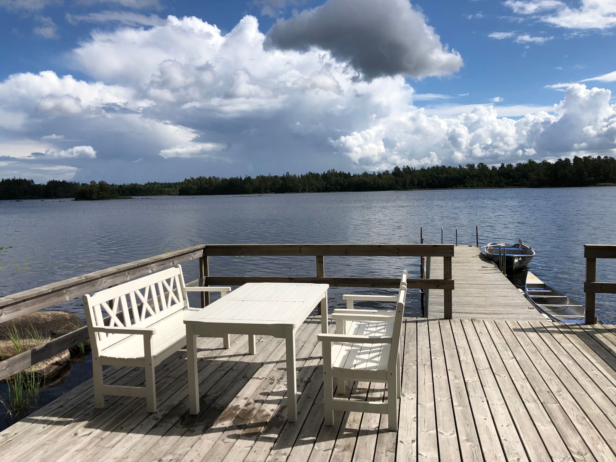 A wooden deck with a table and benches overlooking a lake.