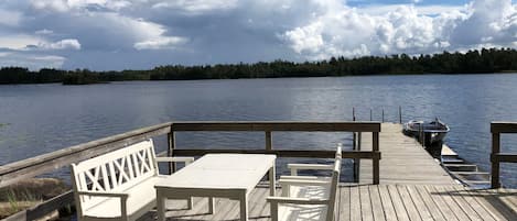 A wooden deck with a table and benches overlooking a lake.