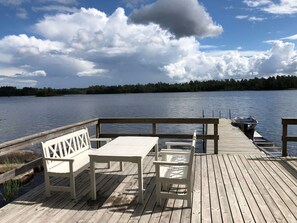 Un terrazza in legno con tavolo e panche vista lago.