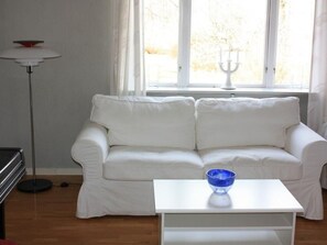 A white sofa, a white coffee table, and a blue bowl on the table. - Schönes Ferienhaus in Småland mit Sauna, Bootssteg zum Schwimmen mit Ruderboot by Interhome (Tingsryd)