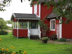 Ein rotes Haus mit Veranda und kleinem Garten.