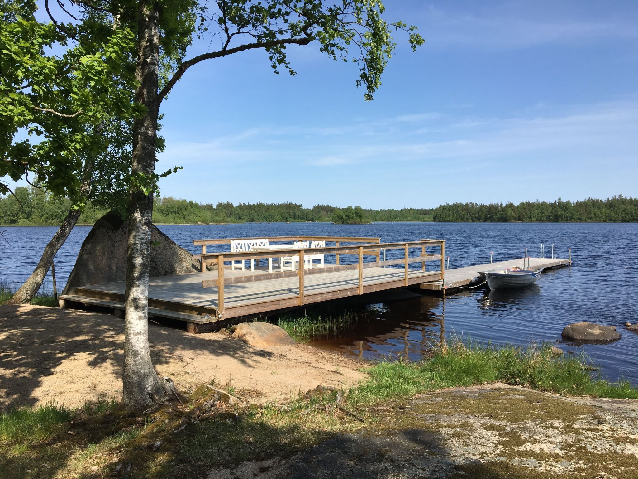 Un molo di legno che si protende su un lago, con panchine e tavoli sulla piattaforma.