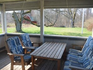 A covered outdoor seating area with wooden furniture and a view of a grassy yard and trees. - Schönes Ferienhaus in Småland mit Sauna, Bootssteg zum Schwimmen mit Ruderboot by Interhome (Tingsryd)