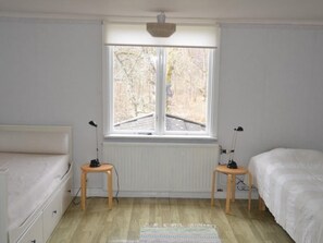 A room with two beds, a window, a radiator, and a rug. - Schönes Ferienhaus in Småland mit Sauna, Bootssteg zum Schwimmen mit Ruderboot by Interhome (Tingsryd)