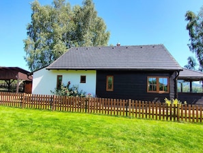 A two-story house with a dark roof, white walls, and a wooden fence.