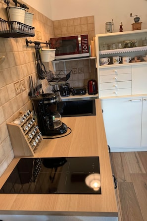 A compact kitchen with a microwave, toaster, coffee maker, and a built-in induction cooktop.
