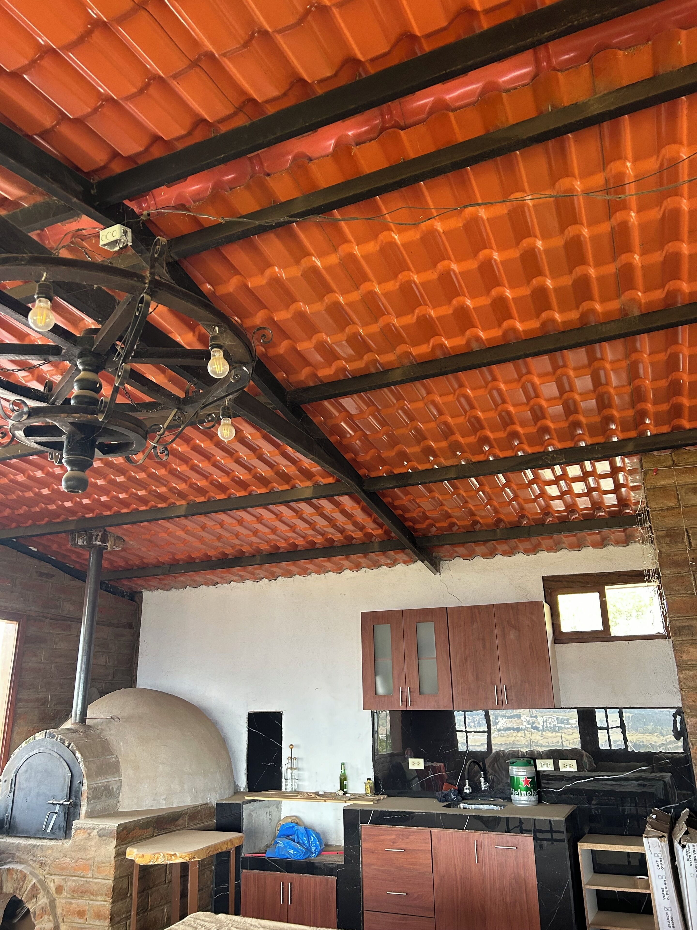 A kitchen with a brick oven, wooden cabinets, and a tiled ceiling.