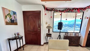 Un saló amb un sofà, una taula de centre amb un vas, una porta de fusta, una làmpada i una vista per una finestra.