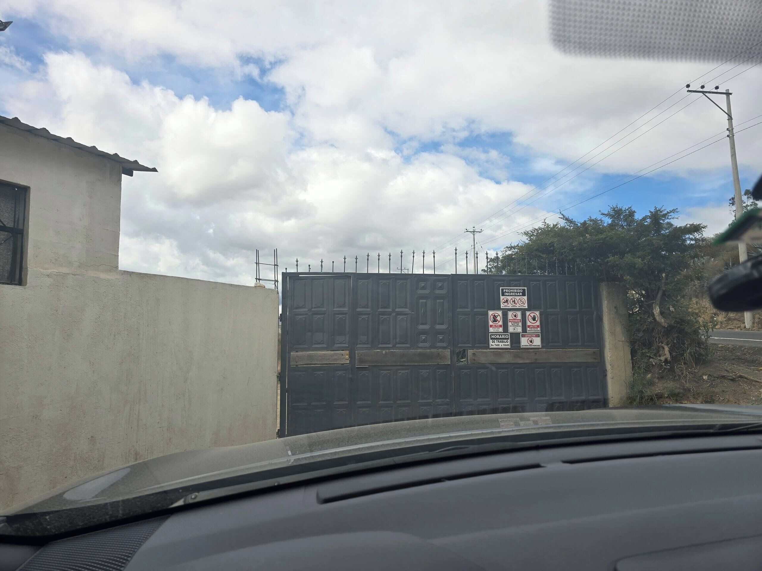Uma entrada fechada por portão, com aviso de proibido a entrada e horários restritos.