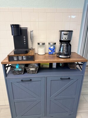 Eine Küchenarbeitsfläche mit Kaffeemaschine, Milchkrug und Gewürzregal.