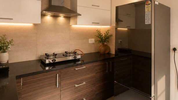 Una cocina moderna con un refrigerador de acero inoxidable, una estufa a gas y armarios de madera.